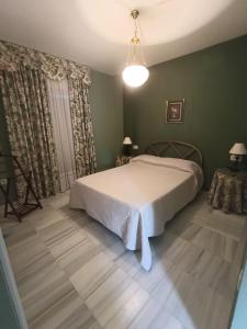 1 dormitorio con cama blanca y paredes verdes en Casa playa El Ancla Puerto Santa María, en El Puerto de Santa María