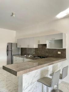 een keuken met witte kasten en een aanrecht met stoelen bij Departamento Céntrico in Monterrey