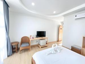 een slaapkamer met een bed en een bureau met een televisie bij Gin's Greenery Resort in Ban Hua Wiang