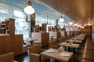 un restaurante con mesas de madera, sillas y luces en Aeropolis Hotel, en Moscú