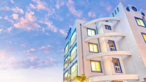 ein hohes weißes Gebäude mit einem wolkigen Himmel im Hintergrund in der Unterkunft Gangneung Basecamp Pension in Gangneung