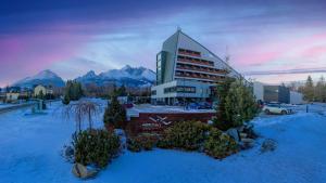 a building with mountains in the background with snow at Horizont Resort in Tatranská Lomnica