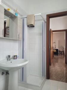 een badkamer met een wastafel en een glazen douche bij La casa di Sergiò in Belgioioso