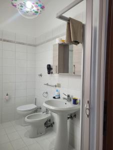 een witte badkamer met een wastafel en een toilet bij La casa di Sergiò in Belgioioso +7 foto's