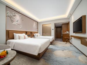 a hotel room with two beds and a television at Guangdong Hotel in Guangzhou