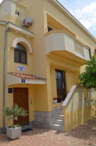 Cette maison jaune dispose d'un balcon et d'un escalier. dans l'établissement Guesthouse Barić, à Zadar