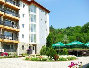a hotel with green umbrellas and flowers in a courtyard at Hotel Monteoru in Sărata-Monteoru