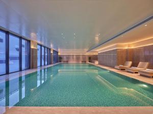 Una piscina en un hotel con sillas y ventanas. en Conrad Altay Hemu, en K'u-mu