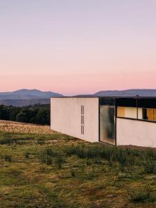 un edificio en un campo con montañas en el fondo en Triptych - The Blunt House, en Koonya