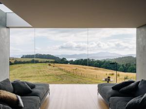 a living room with a large window with a view of a field at Triptych - The Blunt House in Koonya +40 photos