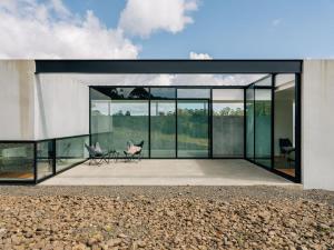 a glass house with two chairs on a patio at Triptych - The Blunt House in Koonya