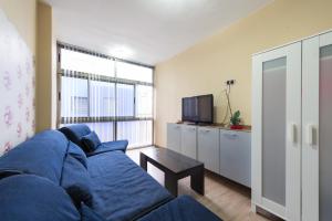 a living room with a blue couch and a tv at Green wateratthebeach in Las Palmas de Gran Canaria