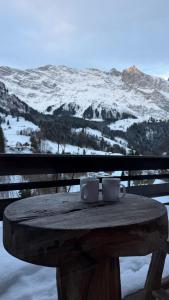 Twee koffiekopjes staan op een tafel met een besneeuwde berg op de achtergrond. bij Chalet Engelberg Mountain View in Engelberg
