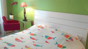 a bedroom with a bed and a red chair at La Pause Bleue in Dinard