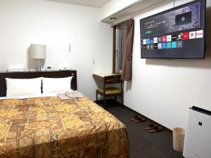 a hotel room with a bed and a flat screen tv at Hotel Tokeidai in Sapporo