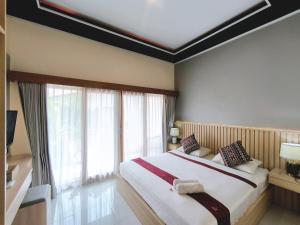 a bedroom with a large bed and a large window at Surya Pandawa Homestay in Uluwatu