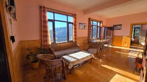 a living room with a table and chairs and windows at Thakur homes- couple and family friendly homestay in Shimla