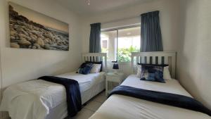 two twin beds in a room with a window at La Crete Sands no 3 in Uvongo Beach +87 photos