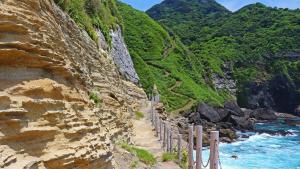 MeraA private log house in a secluded beach, LOGOUT的海边一座岩石山，旁边有一道栅栏