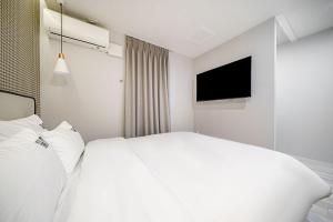 a hotel room with a white bed and a tv at 광안비치호텔더엠 in Kwangan-dong