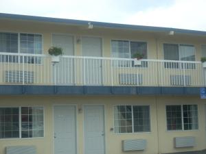 a yellow house with white doors and a balcony at Economy Inn Seaside in Seaside