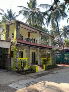 un bâtiment jaune avec un balcon et des palmiers dans l'établissement Dwarka holiday home, à Nagaon