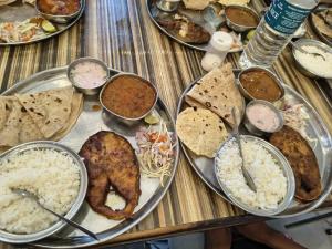 une table avec de nombreuses assiettes de nourriture dessus dans l'établissement Dwarka holiday home, à Nagaon 32 autres photos
