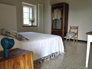 ein Schlafzimmer mit einem Bett, einer Kommode und einem Stuhl in der Unterkunft I Calleri Garden and Rooms in Millesimo