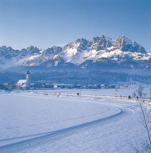 een met sneeuw bedekte bergketen met een stad en een kerk bij Haus St. Michael in Oberndorf in Tirol
