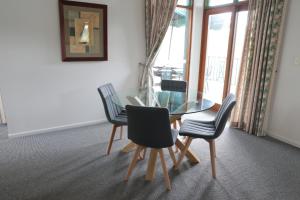 comedor con mesa de cristal y 4 sillas en Puffers Inn, en Loganholme