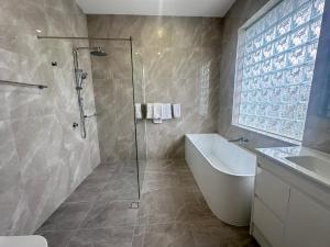 Un baño con ducha, bañera y lavabo. en Puffers Inn, en Loganholme