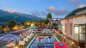 a hotel with a pool and tables and chairs at Gapyeong Ttonggangaji Kids Poolvilla in Gapyeong