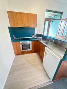 Una cocina con gabinetes de madera y un refrigerador blanco. en Puffers Inn, en Loganholme