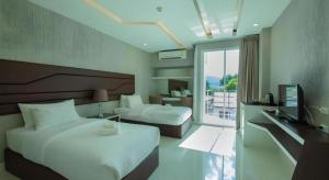 Una habitación de hotel con dos camas y un televisor. en Phuglong Hotel, en Phayao 179 fotos más