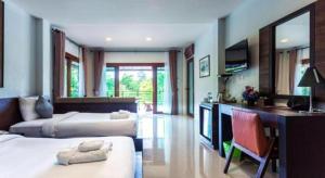 a hotel room with two beds and a desk and a television at Tamali Hotel in Ban Yuan Lae