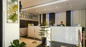 Un vestíbulo con dos personas sentadas en un mostrador de recepción. en Eighty Eight Hotel, en Koronadal