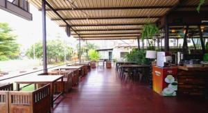 a restaurant with wooden tables and chairs and a large ceiling at I Hotel in Ban Noi Pho Kham