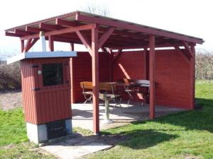 Un pabellón rojo con una mesa y una mesa de picnic. en Ferienwohnungen Hohen Niendorf bei Kühlungsborn, en Hohen Niendorf