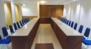 una sala de conferencias con sillas azules y una mesa larga en The Garden Hotel, en Gorontalo