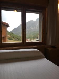 a bedroom with a bed and a window with mountains at Hotel La Braña in San Isidro