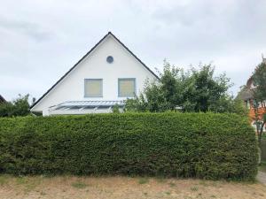 ein Haus mit einem Dach über einer Hecke in der Unterkunft Ferienwohnung mit Garten in Wieck