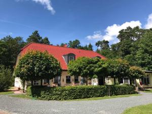 ein Haus mit rotem Dach und zwei Bäumen in der Unterkunft Ferienwohnung Seeblick in Waren (Müritz) + 19 Fotos