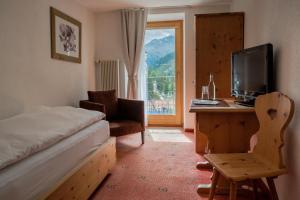 Una habitación de hotel con una cama, un escritorio y una ventana. en Hotel Bernina, en Pontresina