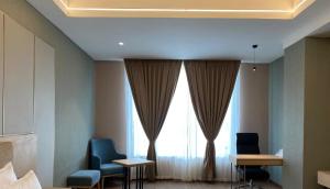 Habitación con 2 sillas y ventana grande. en Hotel P4 City Center Jabalpur, en Jabalpur