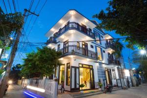 a white building with lights on it at night at Quynh Chau Homestay Hội An in Hoi An