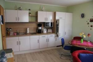 une cuisine avec des armoires blanches et une table dans une pièce dans l'établissement Bungalow mit Terrasse, à Glowe
