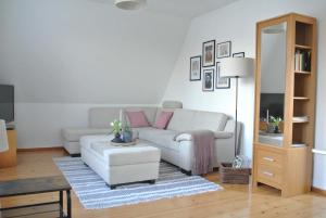 een woonkamer met een witte bank en een tafel bij FischLANDinSicht in Ribnitz-Damgarten +10 foto's