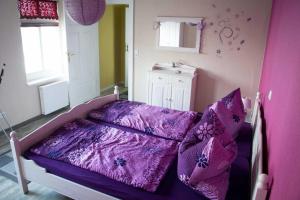 een kleine slaapkamer met een paars bed met kussens bij Ferienwohnung Sassnitz mit Meerblick in Sassnitz