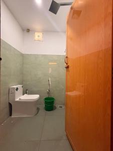 a bathroom with a toilet and a green bucket at Western Castle Stay n lawn in Coimbatore