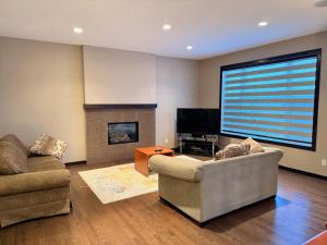 a living room with two couches and a flat screen tv at Panorama Haven in Calgary